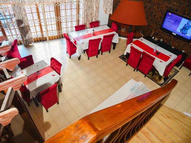 Spacious open-plan dining area featuring a large built-in fireplace, tiled flooring, and direct access to the patio through security-gated glass doors.