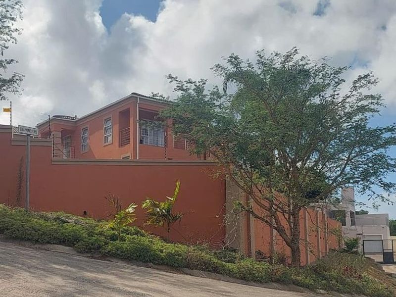 Street view of the property featuring a prominent perimeter wall with electric fencing and a paved driveway entrance.