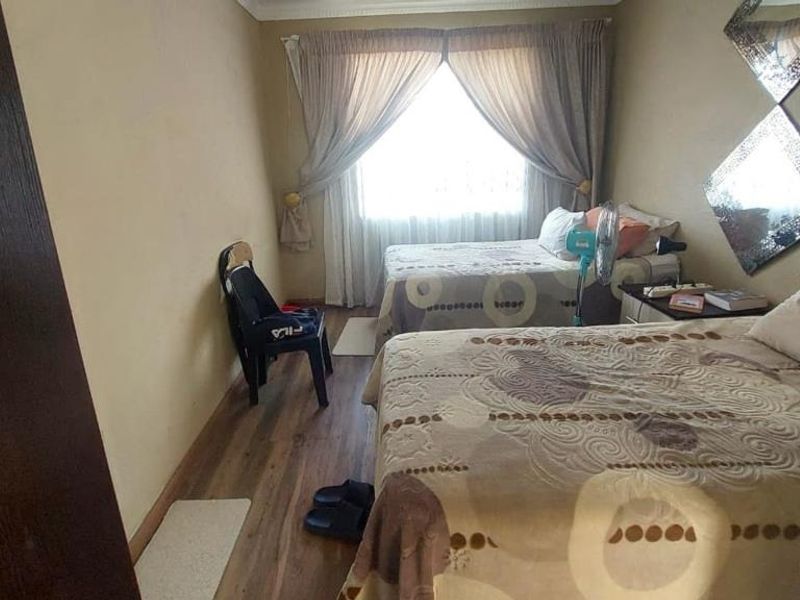 A functional bedroom featuring laminate flooring and window treatments, offering a comfortable space with potential for modern updates.