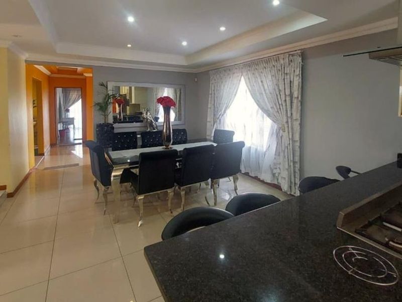 Spacious open-plan living and dining area featuring tiled floors, recessed lighting, and a modern kitchen with granite countertops and a gas hob.