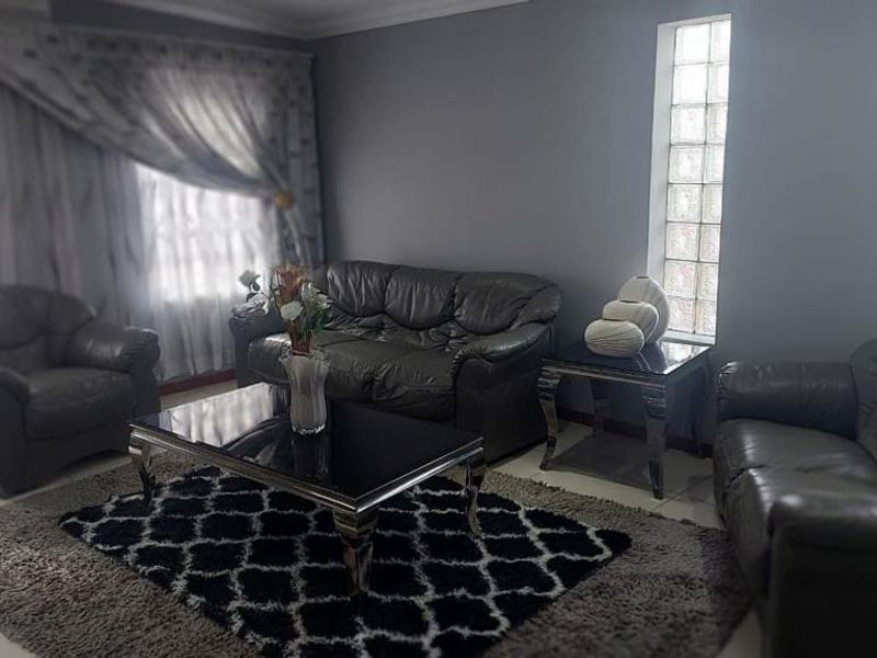 A living room featuring tiled flooring, coved ceilings, and distinctive glass block windows, providing a neutral base for interior design updates.