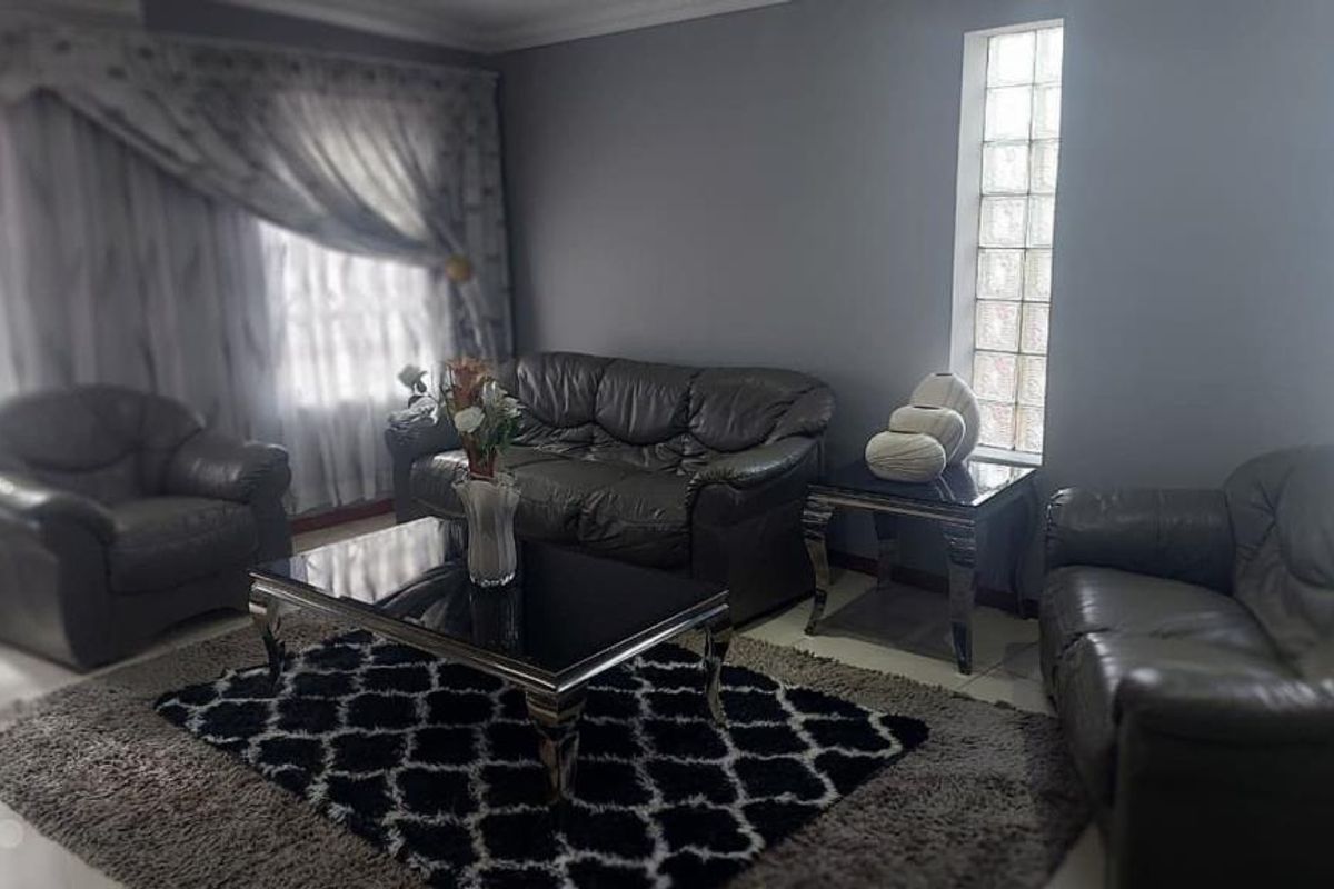 A living room featuring tiled flooring, coved ceilings, and distinctive glass block windows, providing a neutral base for interior design updates.