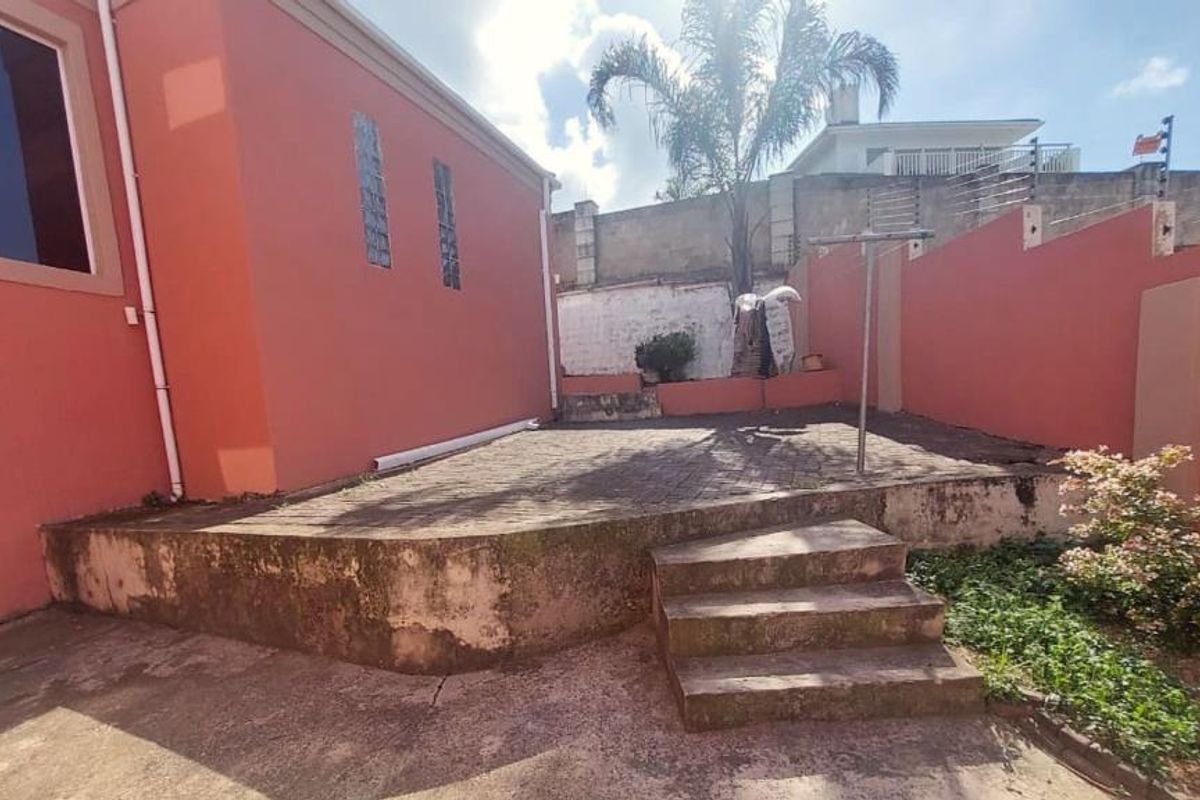 Rear exterior area featuring a paved patio, concrete stairs, and perimeter wall with electric fencing, offering potential for outdoor living space improvement.