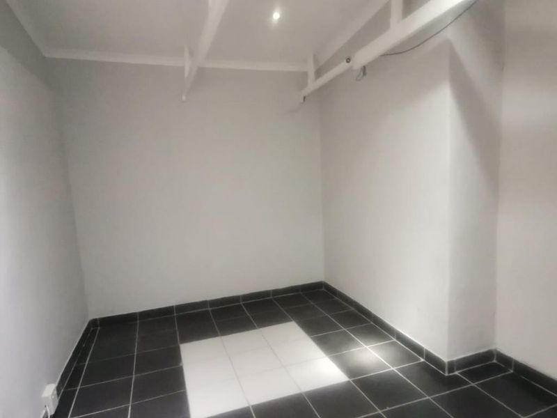 A clean, empty utility space featuring high ceilings with exposed beams and contrasting black and white tiled flooring.