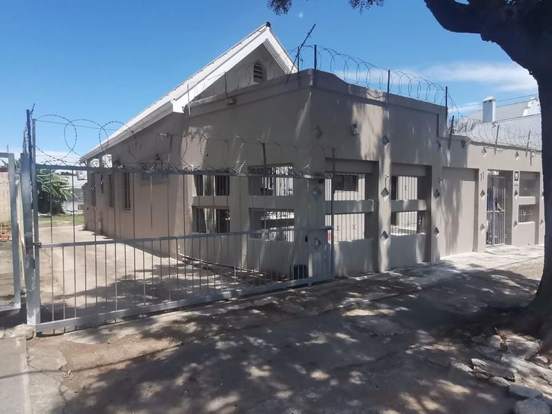 Exterior view of a commercial property featuring a secure perimeter fence with razor wire, concrete facade, and gated entrance.