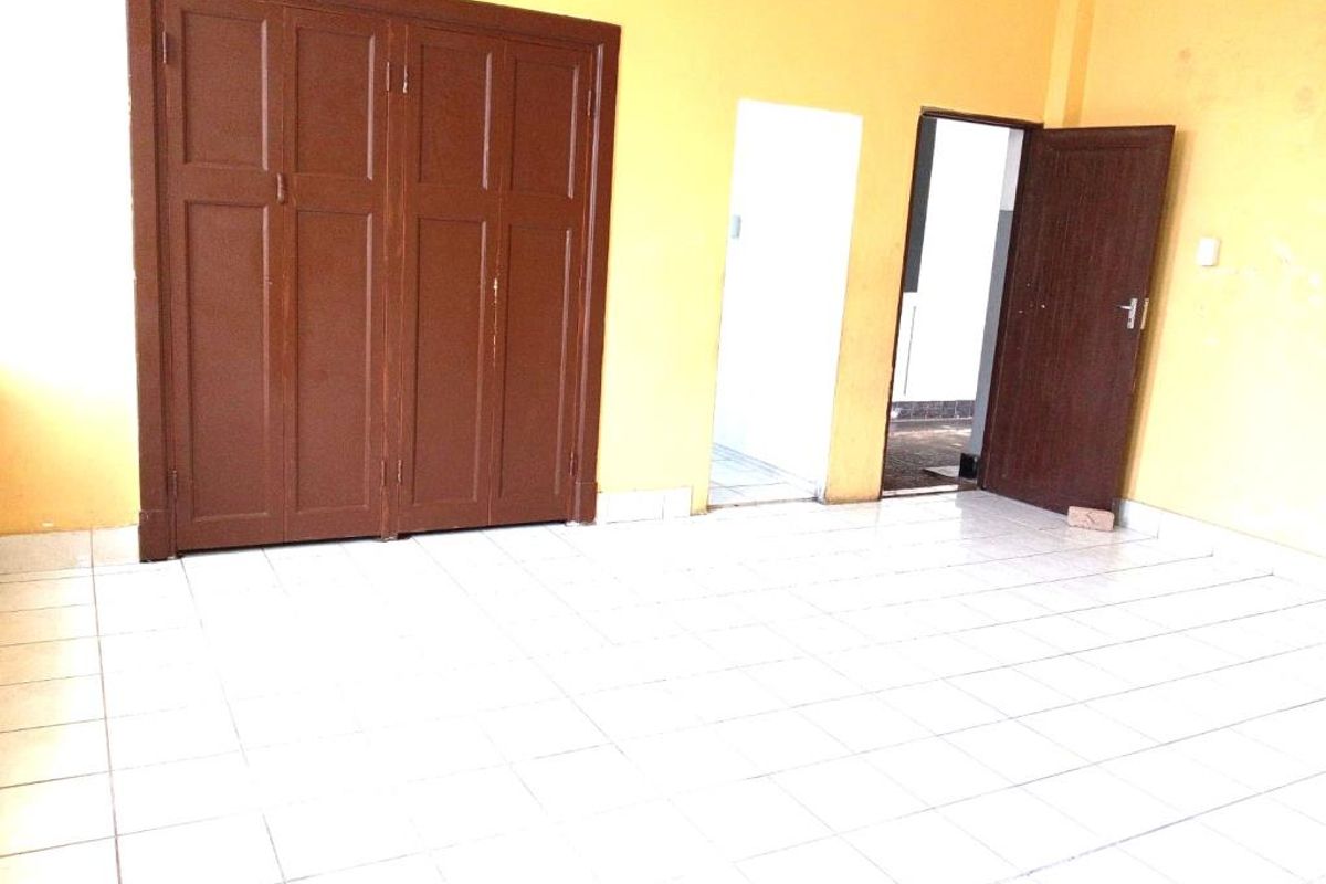 An empty room featuring tiled flooring, built-in wooden cabinetry, and access to adjacent spaces through internal doorways.