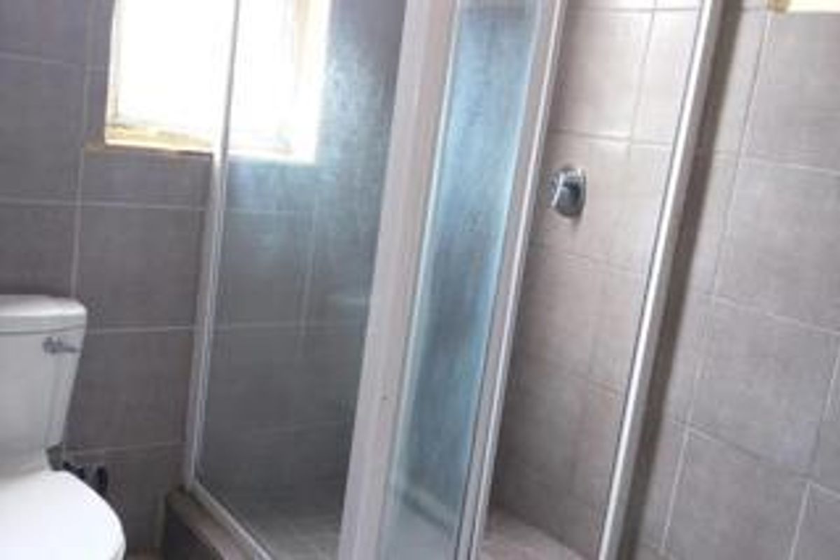 A functional bathroom featuring a tiled shower enclosure with a glass door and a standard toilet.