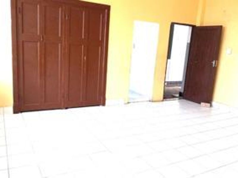 A vacant bedroom featuring built-in wooden cabinetry, tiled flooring, and access to an adjoining room.