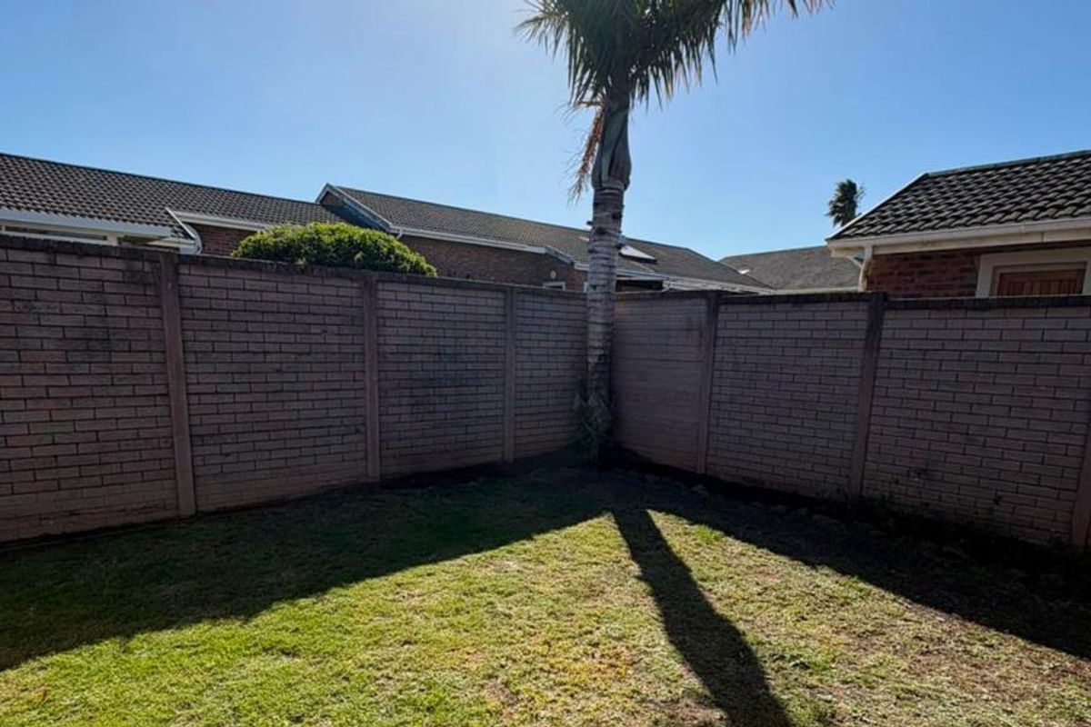 A private rear garden area featuring a brick boundary wall and a small lawn space.