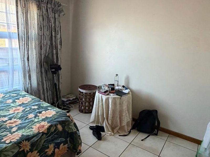 A standard bedroom featuring tiled flooring and a large window, providing natural light to the space.