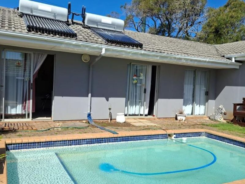 Exterior view of the property featuring a swimming pool, solar water heating panels on the roof, and direct access via sliding glass doors.