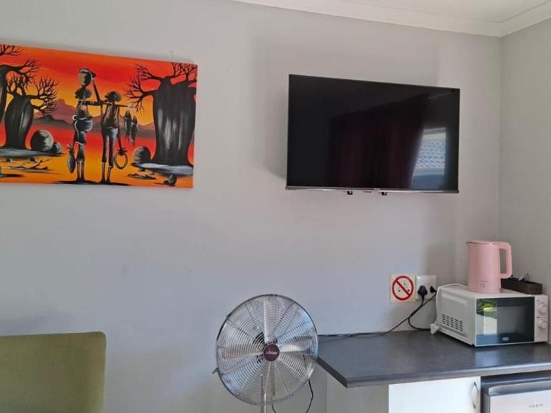 A living area featuring a wall-mounted television and a small kitchenette counter with built-in cabinetry.