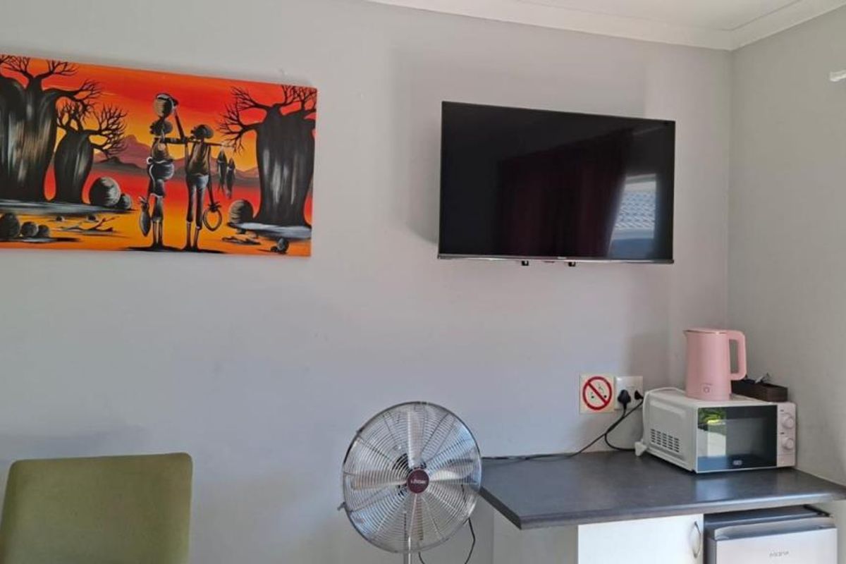 A living area featuring a wall-mounted television and a small kitchenette counter with built-in cabinetry.