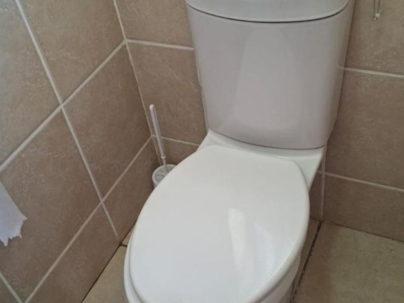 A compact bathroom featuring a standard white toilet and neutral ceramic wall and floor tiling.