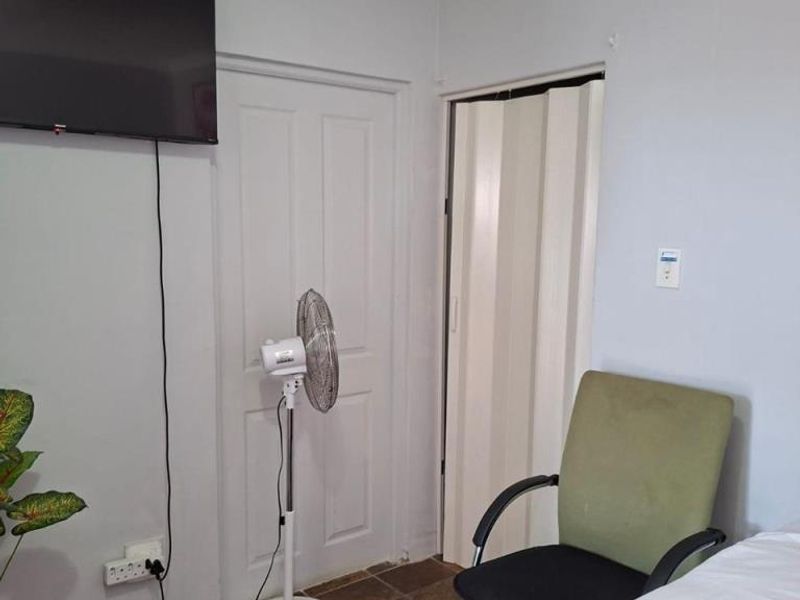 A bedroom featuring tiled flooring, a standard door, and a folding door leading to an adjacent space.