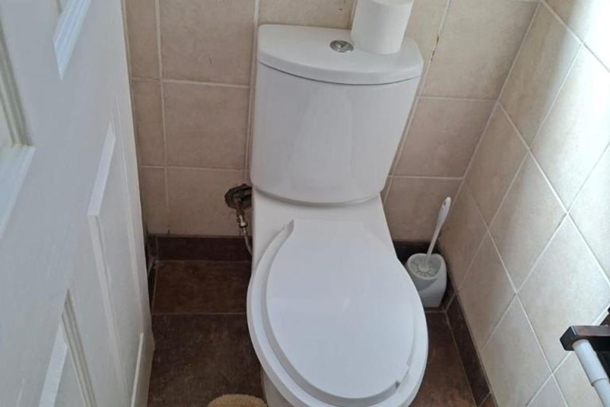 A compact bathroom featuring a standard white toilet, tiled walls, and tiled flooring.