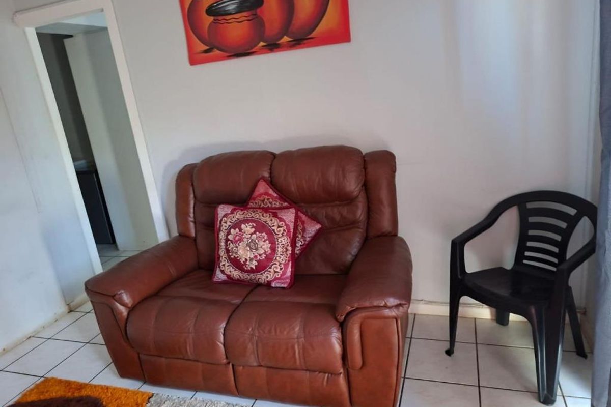 A living room area featuring tiled flooring and a doorway leading to an adjacent space.