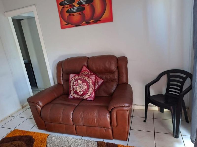 A living room area featuring tiled flooring and a doorway leading to an adjacent space.