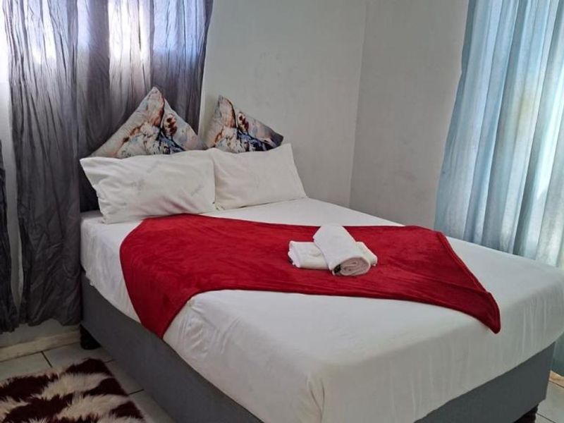 A bedroom featuring tiled flooring and a wall-mounted air conditioning unit.