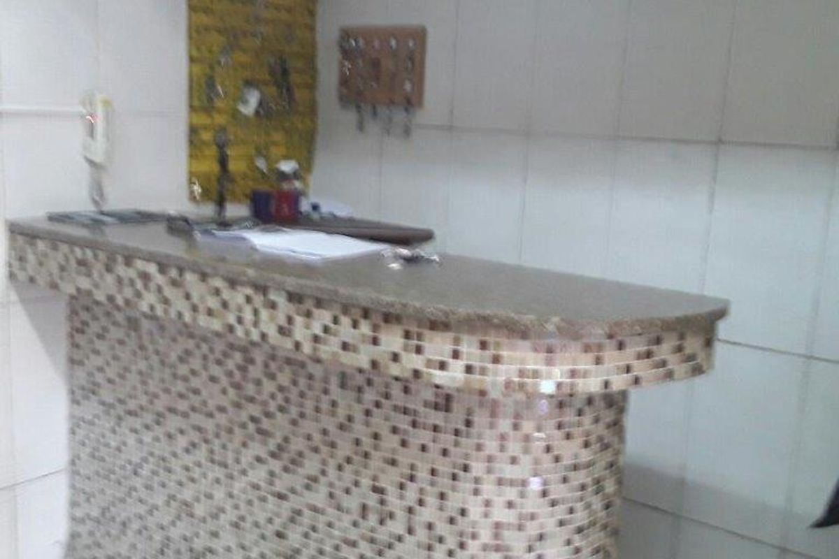 A small kitchen area featuring a tiled breakfast bar and tiled wall finishes, currently in need of cosmetic updates.