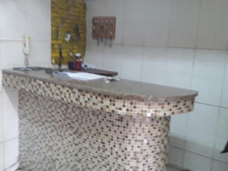 A small kitchen area featuring a tiled breakfast bar and tiled wall finishes, currently in need of cosmetic updates.