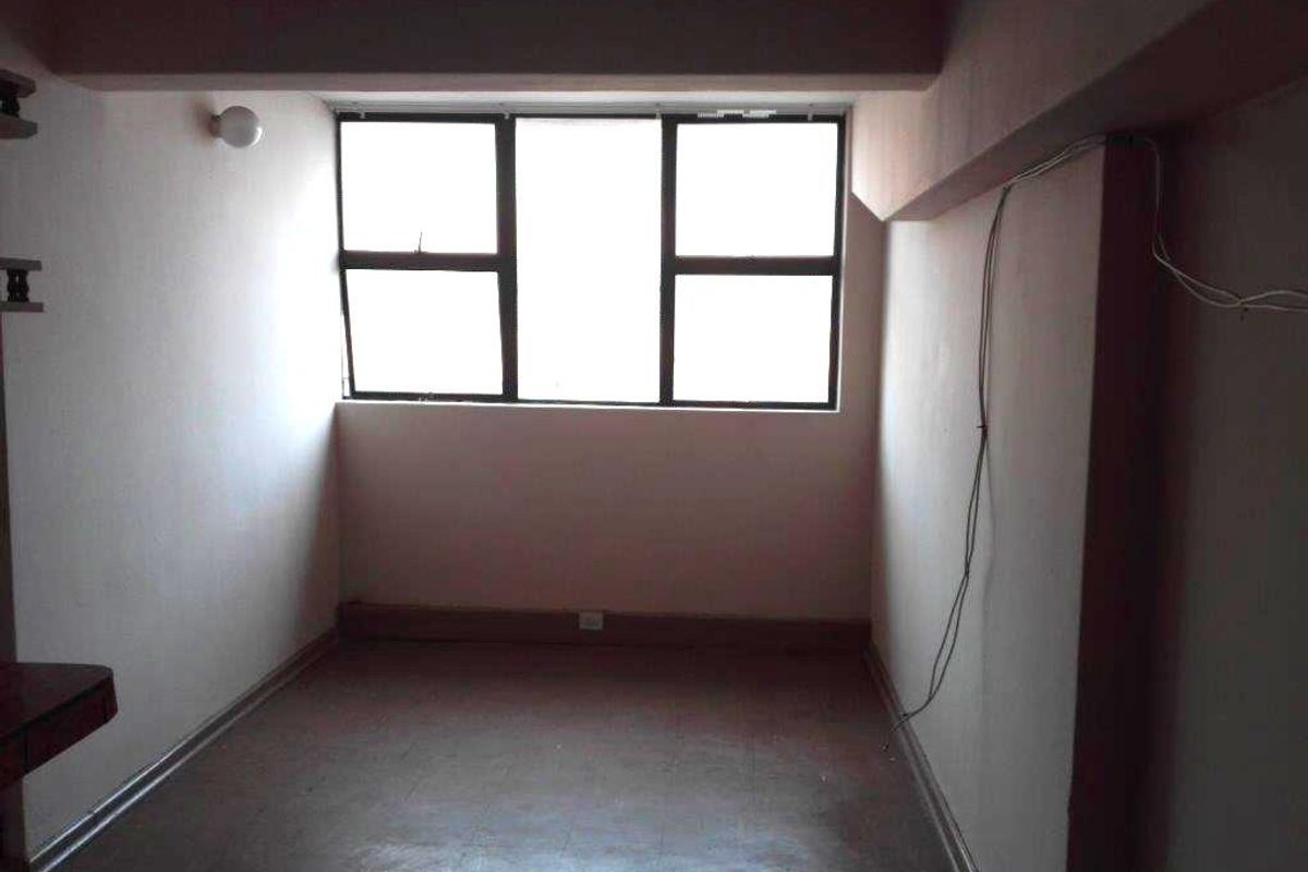 An empty bedroom featuring aluminum window frames and basic flooring, requiring minor cosmetic updates and electrical cable management.