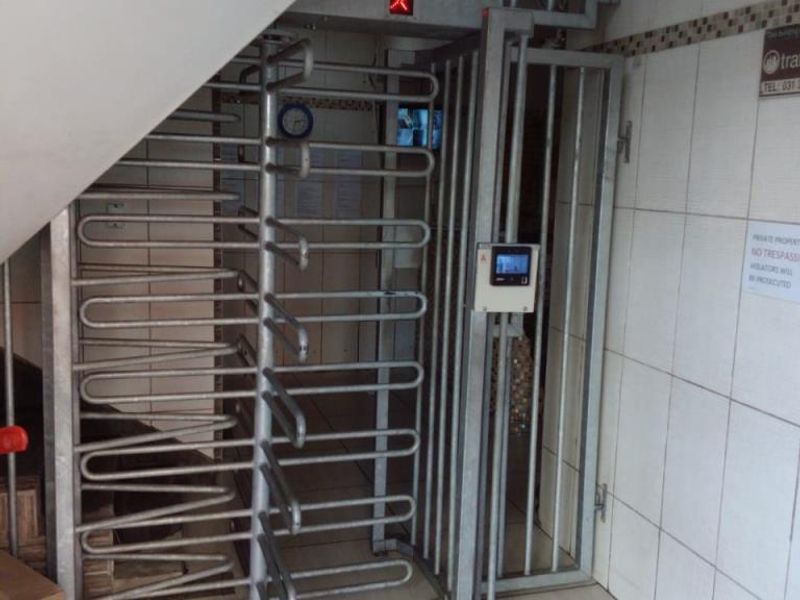 A secure building entrance featuring a metal turnstile, access control system, and tiled finishes.