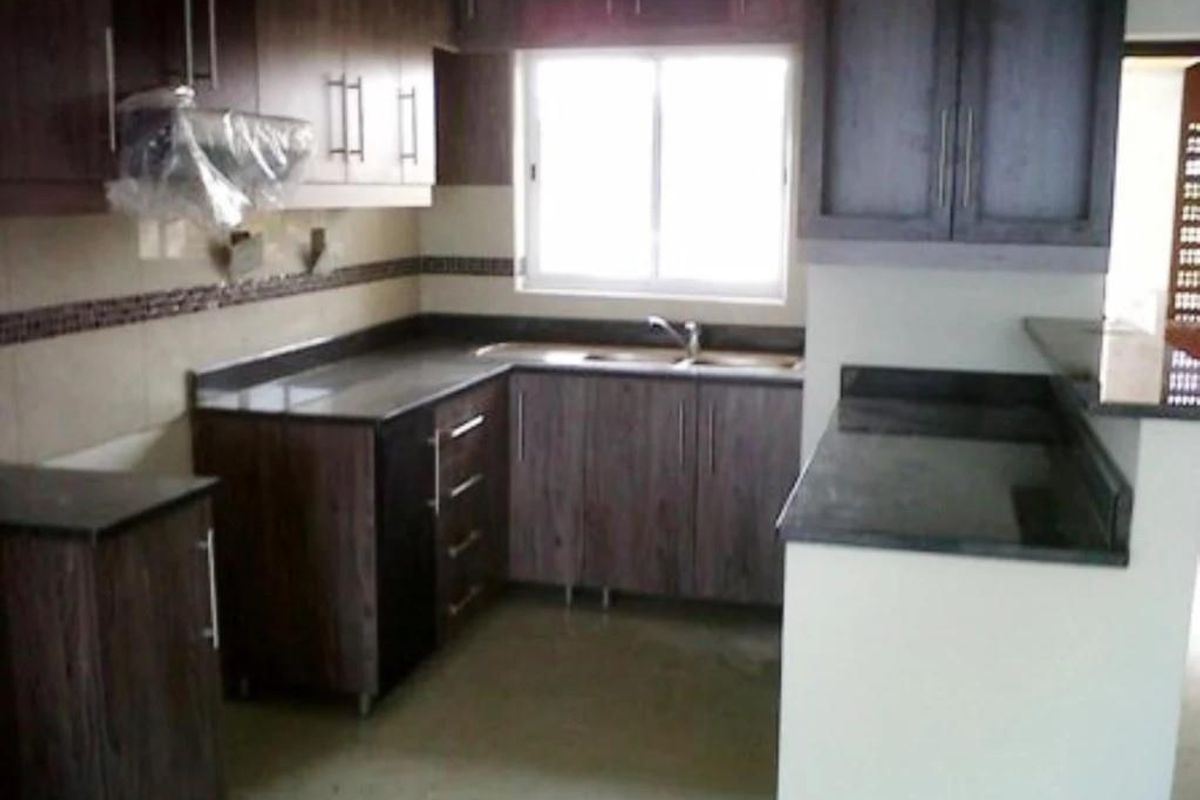 A functional kitchen featuring dark wood-grain cabinetry, granite countertops, a double-basin sink, and a built-in extractor fan.