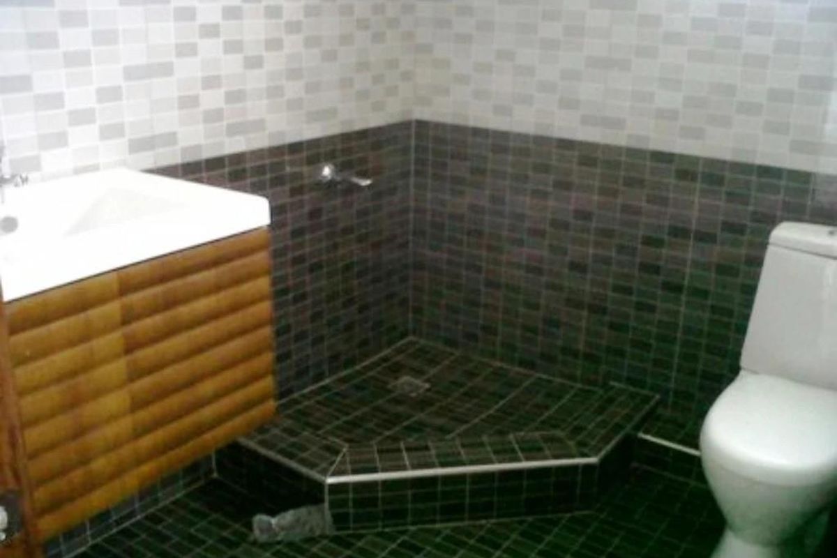 A functional bathroom featuring a corner shower enclosure, a wall-mounted vanity unit with integrated basin, and a standard toilet.