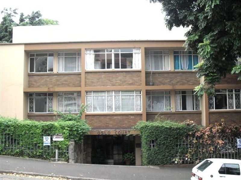 Front elevation of Oslo Court apartment building featuring a brick facade, metal-framed windows with security bars, and a ground-level entrance.