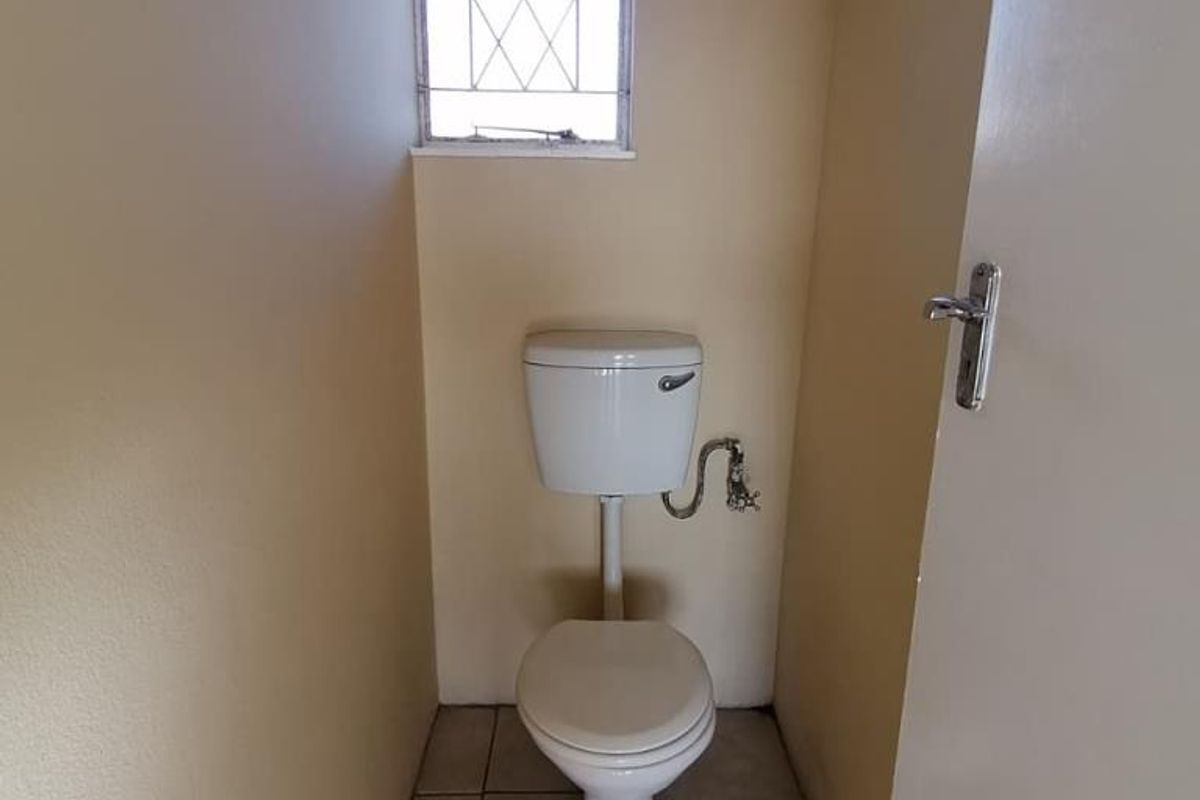 A compact, functional guest toilet featuring tiled flooring and a small window for natural ventilation.