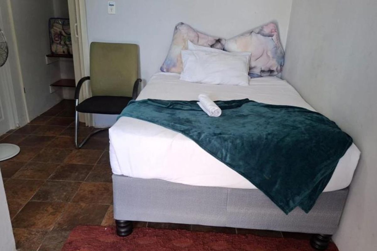A compact bedroom featuring tiled flooring and a small built-in storage area, providing a functional space for rest.