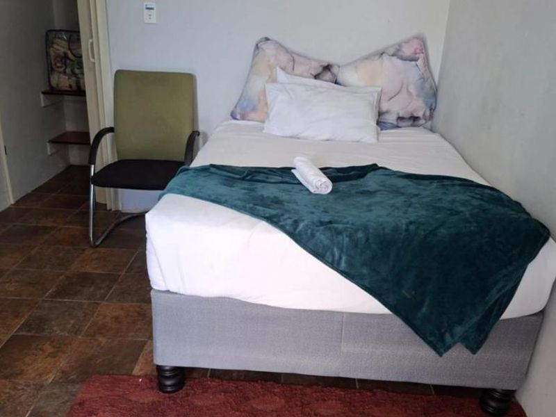 A compact bedroom featuring tiled flooring and a small built-in storage area, providing a functional space for rest.