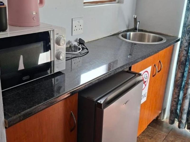Compact scullery area featuring granite countertops, built-in cabinetry, and a stainless steel sink, providing functional prep space.
