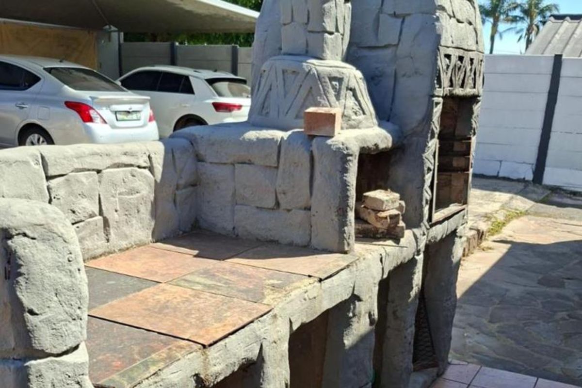 Outdoor area featuring a large, custom-built stone masonry braai with tiled prep surfaces and paved patio flooring.