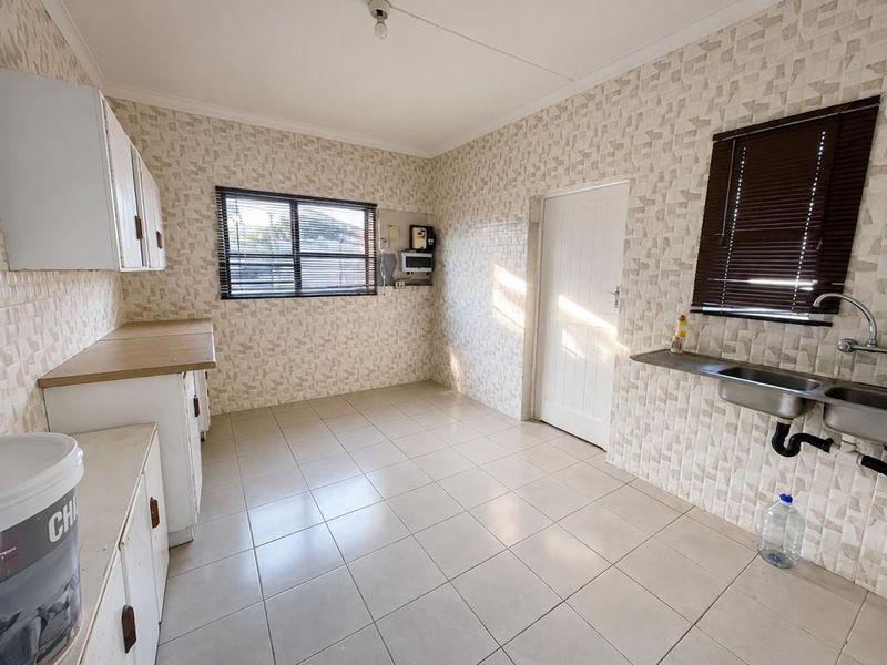 A functional laundry or utility room featuring built-in cabinetry, tiled flooring, and a wall-mounted sink.