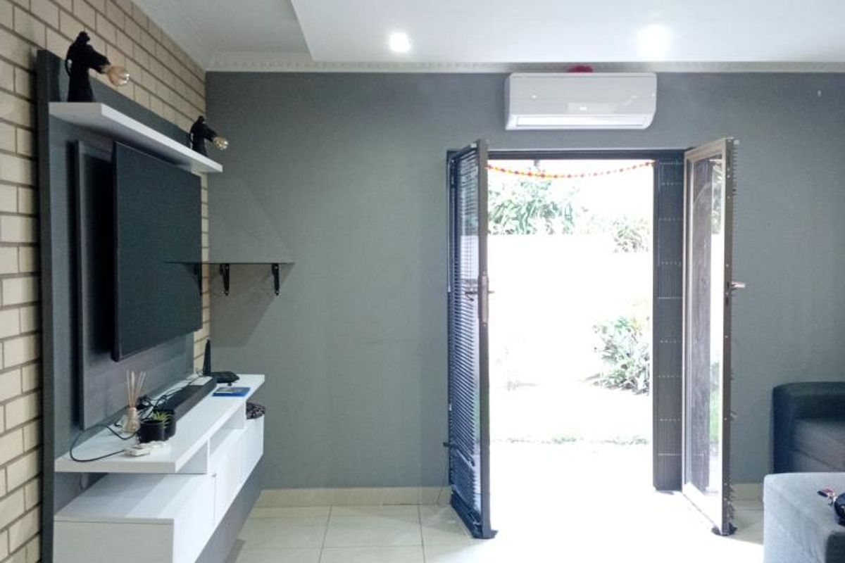 Modern living area featuring a built-in media console, brick feature wall, recessed ceiling lighting, and direct access to an outdoor space via double doors.