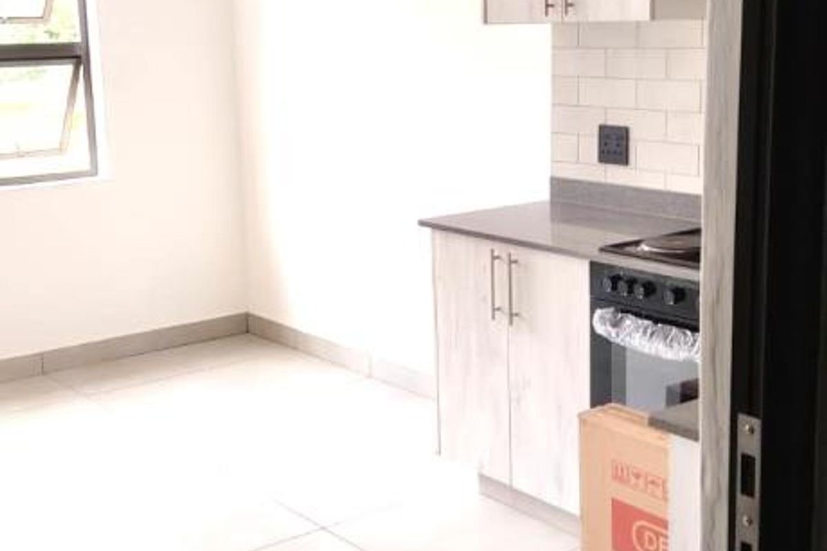 A modern, minimalist kitchen featuring light wood-grain cabinetry, subway tile backsplash, and tiled flooring, presented in a clean, empty state.