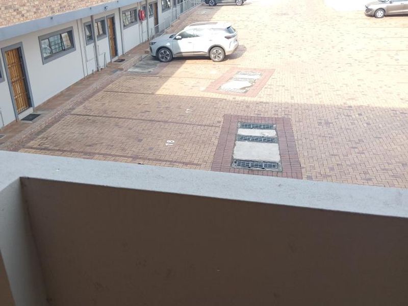 An elevated view of the apartment complex rear parking area, featuring paved surfaces and brick building facades.