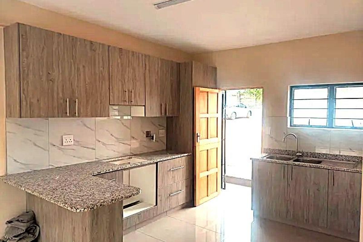 Modern kitchen featuring wood-look cabinetry, granite countertops, marble-look tile backsplash, and tiled flooring, with direct access to the exterior.