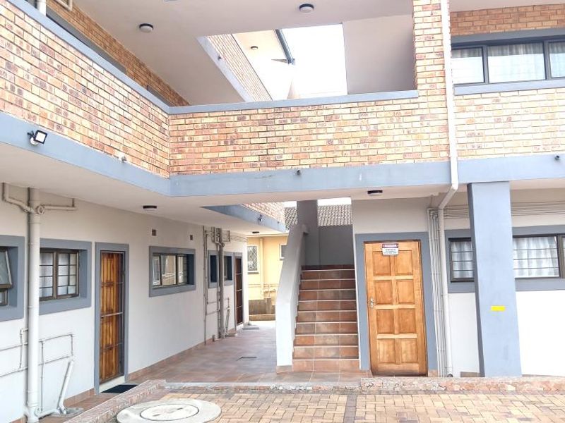 Exterior view of an apartment complex featuring brick facade, paved driveway, and external staircases providing access to upper-level units.