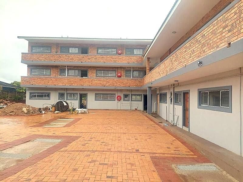 Exterior view of a multi-story apartment building featuring a face brick facade and a paved courtyard area with integrated drainage.