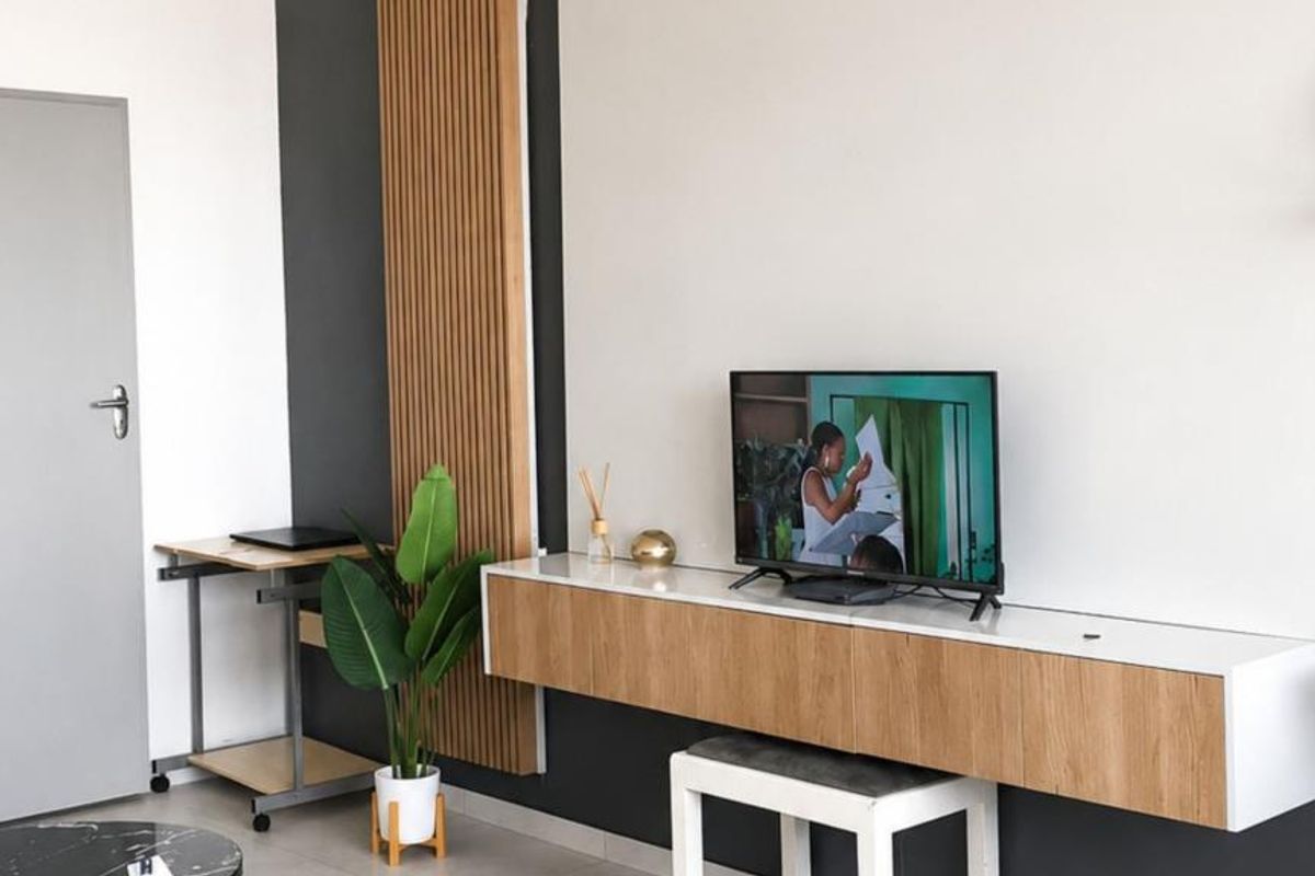 A modern living room featuring a floating media console, stylish slatted wood wall accents, and neutral tiled flooring.
