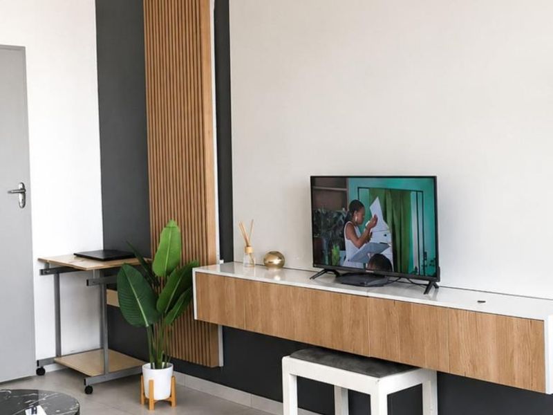 A modern living room featuring a floating media console, stylish slatted wood wall accents, and neutral tiled flooring.