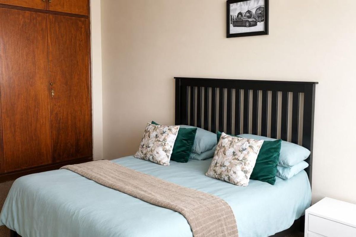 A bedroom featuring a large built-in wooden wardrobe and neutral wall finishes, providing a functional and classic storage solution.