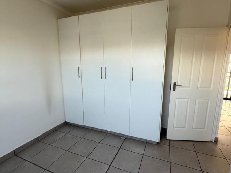 A bedroom featuring built-in white cabinetry, tiled flooring, and a standard interior door.