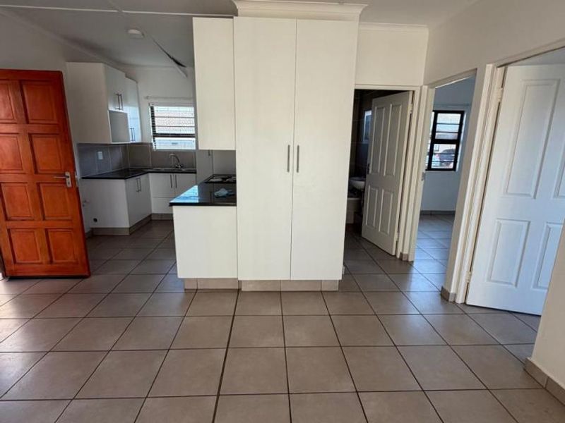 Open plan living area featuring tiled flooring, built-in kitchen cabinetry with dark countertops, and access to adjacent rooms through standard interior doors.
