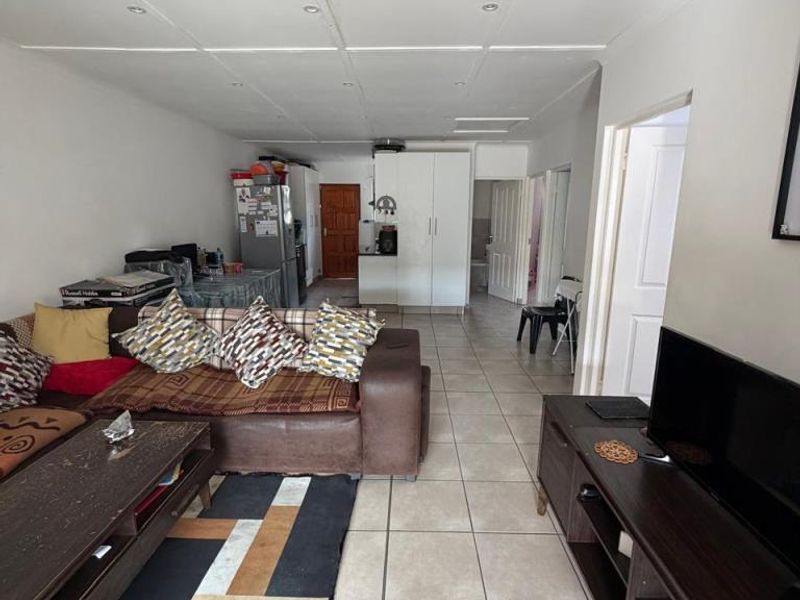 Open plan living area featuring tiled flooring and recessed ceiling lighting, connecting to the kitchen and hallway areas.