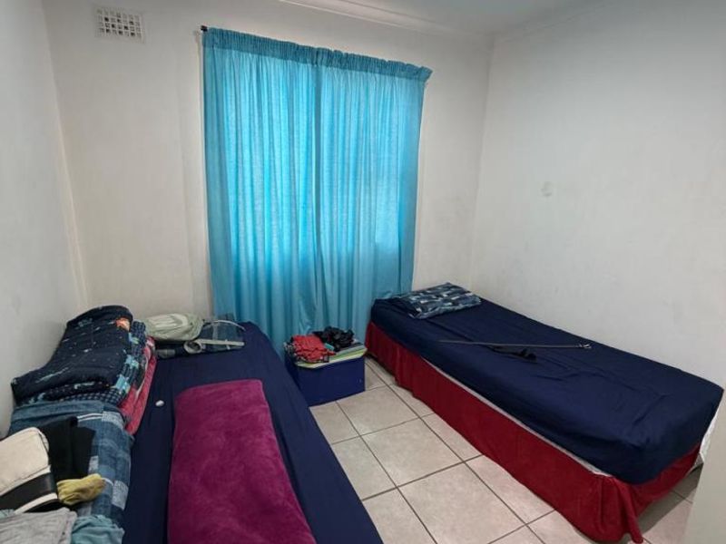A compact bedroom featuring tiled flooring and recessed ceiling lighting, currently utilized as a twin room.