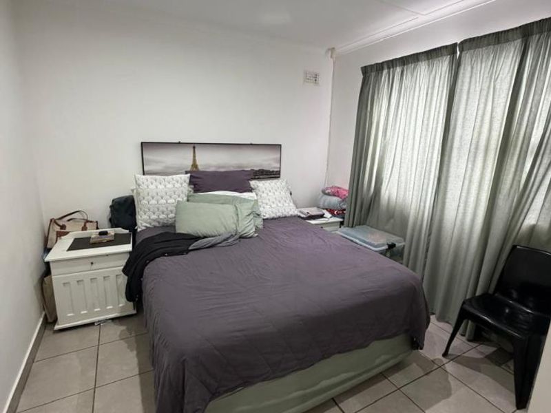 A functional bedroom featuring tiled flooring and recessed downlighting, providing a neutral base for personalization.